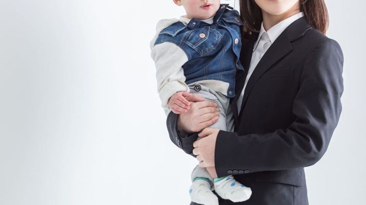 子どもを抱っこするスーツ姿の女性