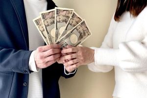 札束を一緒に持つ2人