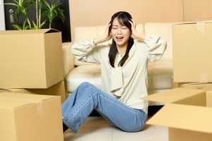 段ボールに囲まれて頭を抱える人