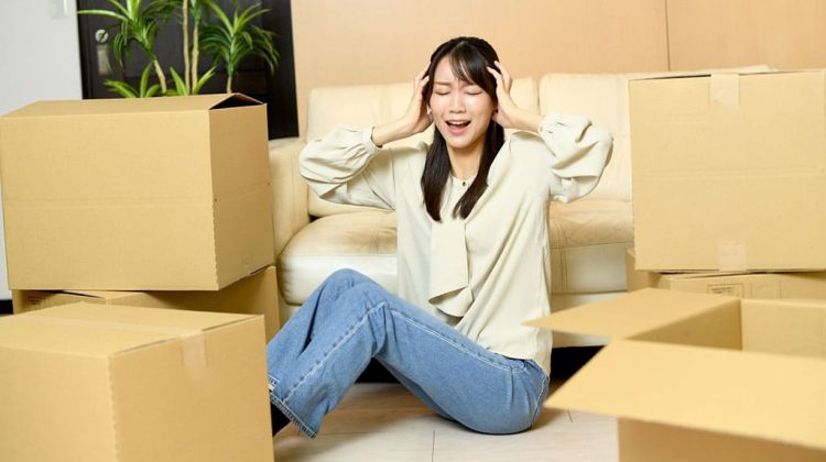 段ボールに囲まれて頭を抱える人